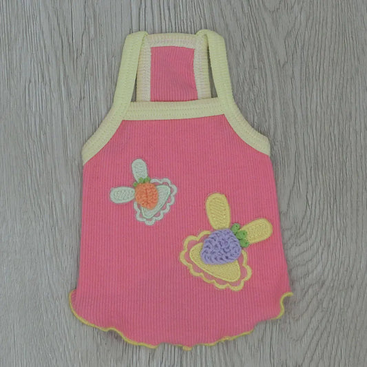 Pink children's dress with floral designs on a wooden surface