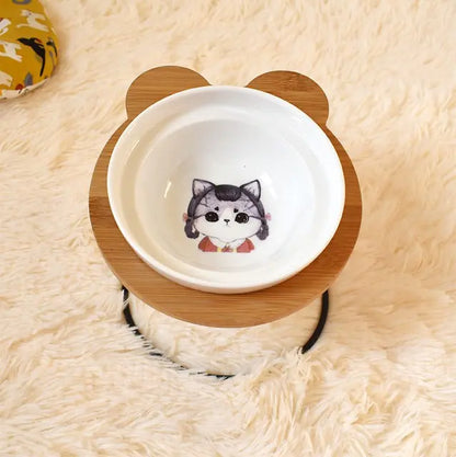 Pet bowl with wooden base featuring a cartoon cat design on a soft beige surface.
