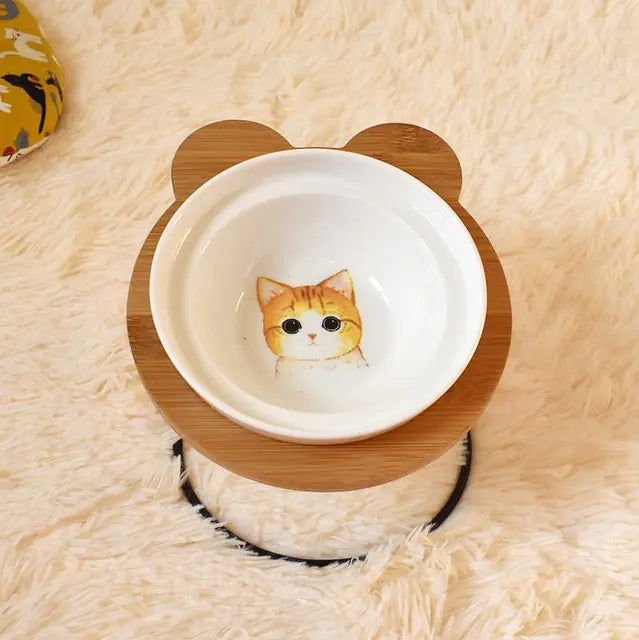 Pet bowl with wooden rim and cat illustration on a fluffy beige surface