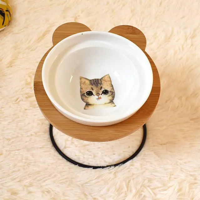 Pet bowl with a wooden base featuring an illustration of a cat on a soft beige surface.