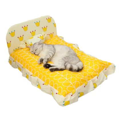 Cat lying on a small yellow and white patterned bed with a white background