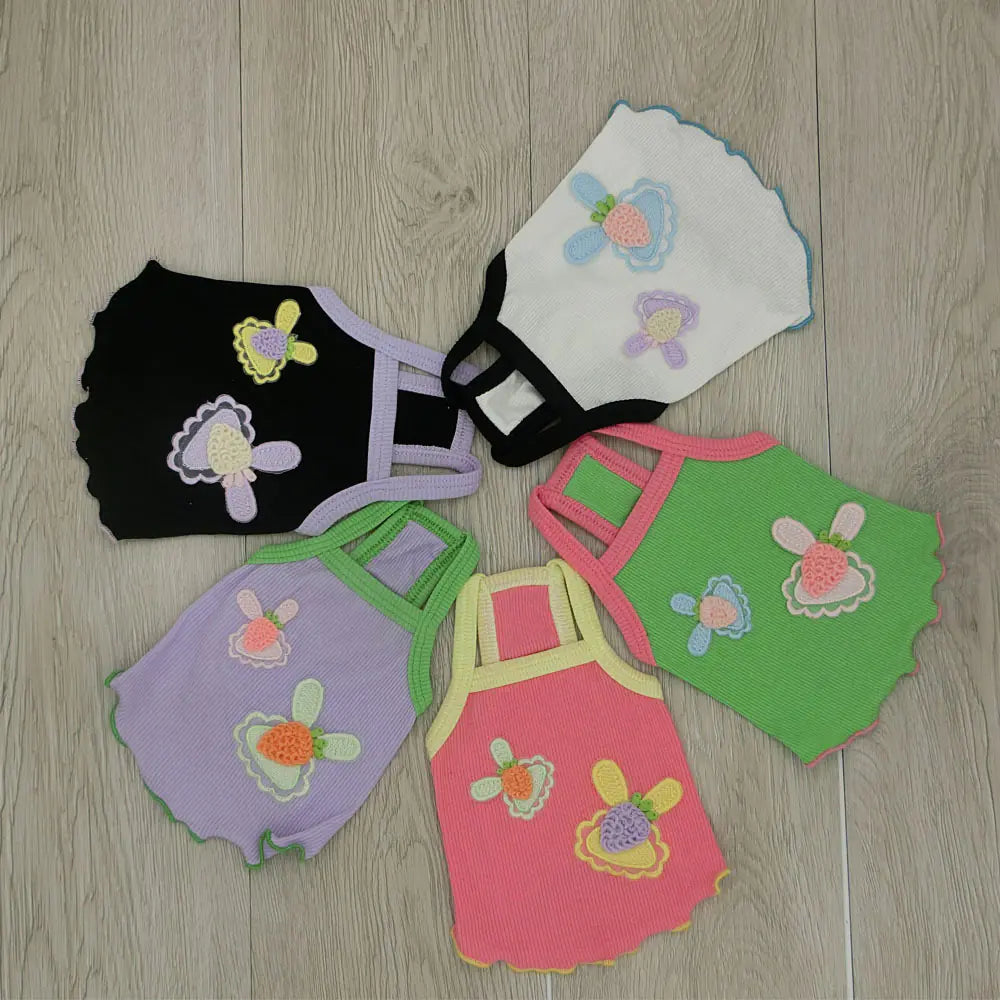 Colorful baby rompers with floral designs on a wooden floor.