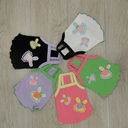 Colorful baby rompers with floral designs on a wooden floor.