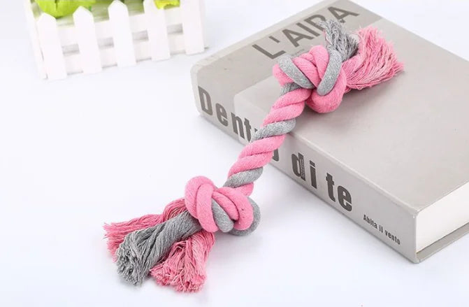 Pink and gray knotted rope toy on a book with 'L'AITA' branding.