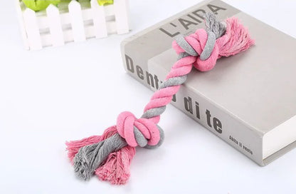 Pink and gray knotted rope toy on a book with 'L'AITA' branding.