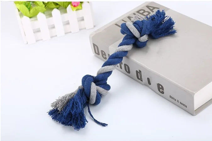 Blue and gray braided rope toy on a white surface with a blurred background